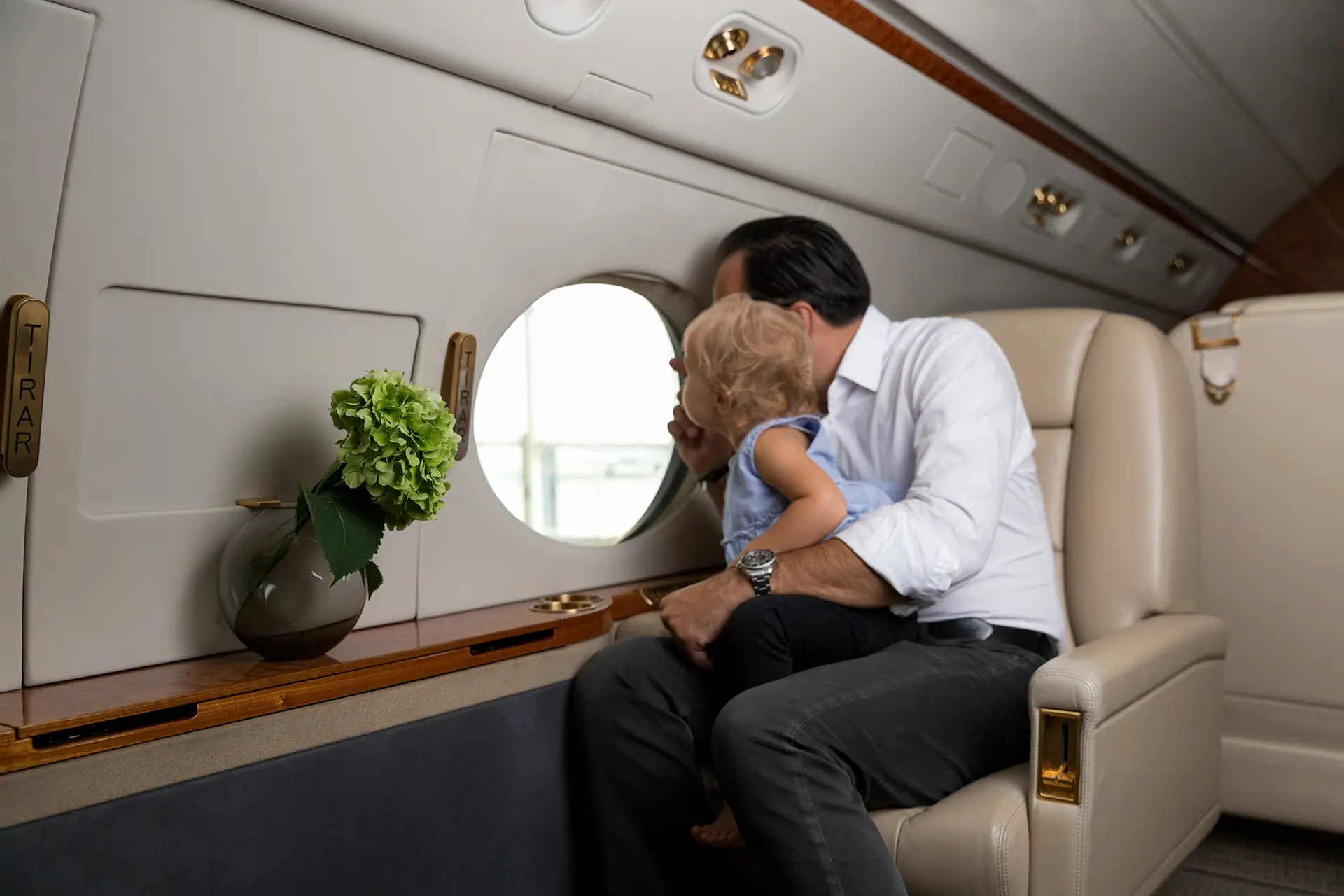 A father and child looking out the window of a business jet, highlighting the personalized and family-friendly aspect of a tailored flight experience.